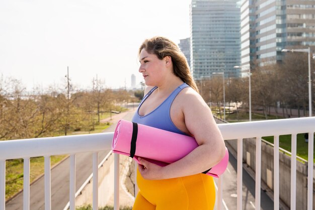 Une jeune femme debout avec un tapis de yoga