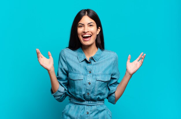 Jeune femme décontractée hispanique se sentant heureuse, excitée, surprise ou choquée, souriante et étonnée de quelque chose d'incroyable