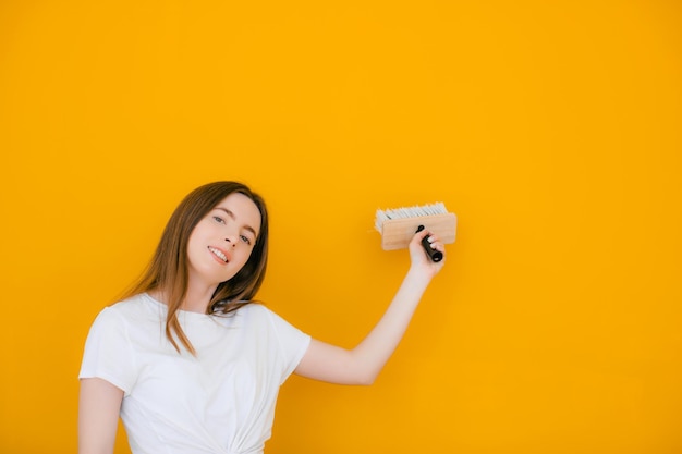 Jeune femme décoratrice avec rouleau à peinture sur fond jaune