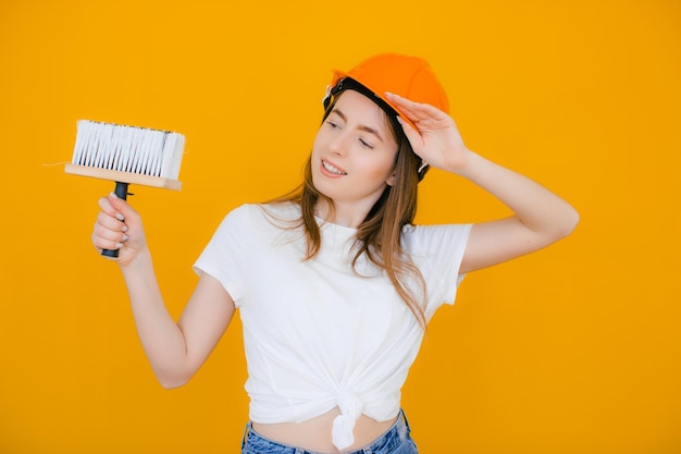 Jeune femme décoratrice avec rouleau à peinture sur fond jaune