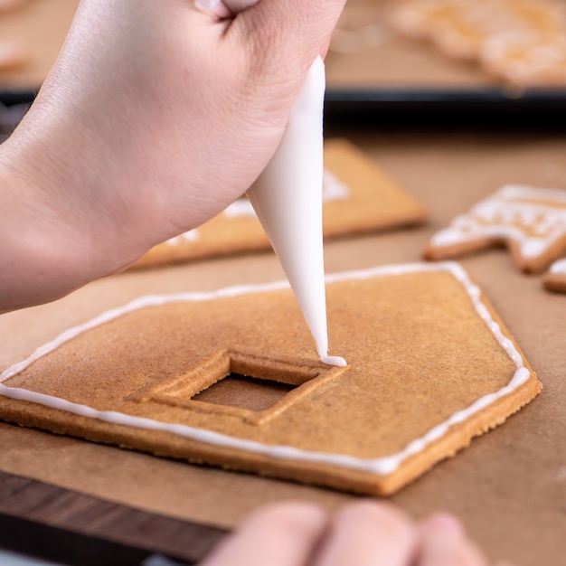 La jeune femme décore des biscuits de pain d'épice de Noël