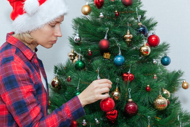 Une jeune femme décore un sapin de Noël