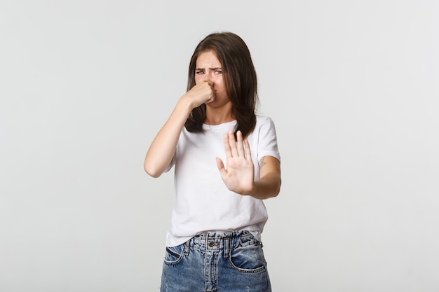 La jeune femme dégoûtée ferma le nez et tendit la main en signe de refus, rejetant quelque chose avec une odeur horrible.