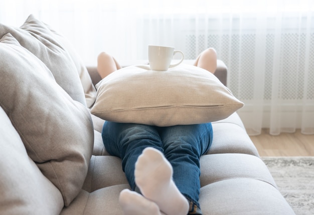 Jeune, femme, délassant, divan, tasse, café, oreiller