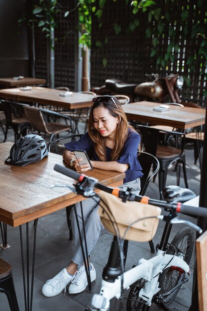 Jeune femme, délassant, utilisation, smartphone, et, coupure, à, café, après, cyclisme