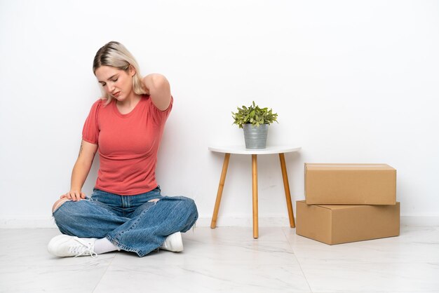 Jeune femme déménageant dans une nouvelle maison parmi des boîtes isolées sur fond blanc avec des maux de cou