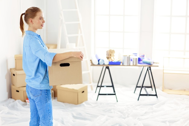 Jeune femme déménageant dans une nouvelle maison tenant des boîtes en carton