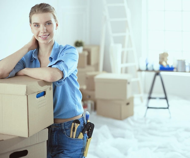 Jeune femme déménageant dans une nouvelle maison tenant des boîtes en carton