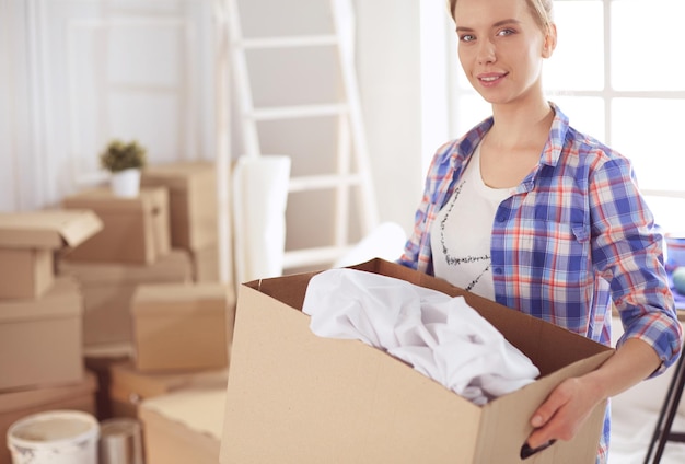 Jeune femme déménageant dans une nouvelle maison tenant des boîtes en carton