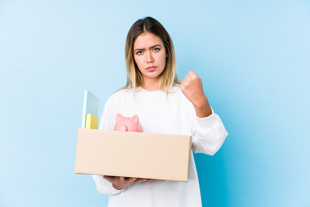 Jeune femme déménageant montrant le poing à la caméra, une expression faciale agressive.