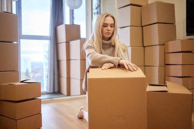 Jeune femme déménageant nouveau lieu et concept de réparation heureuse jeune femme avec de nombreuses boîtes en carton assis