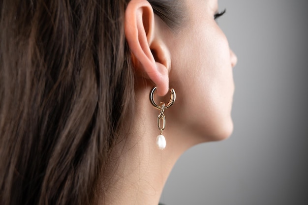 Jeune femme démontrant des boucles d'oreilles dorées élégantes vue recadrée Bijoux à la mode Photo de haute qualité