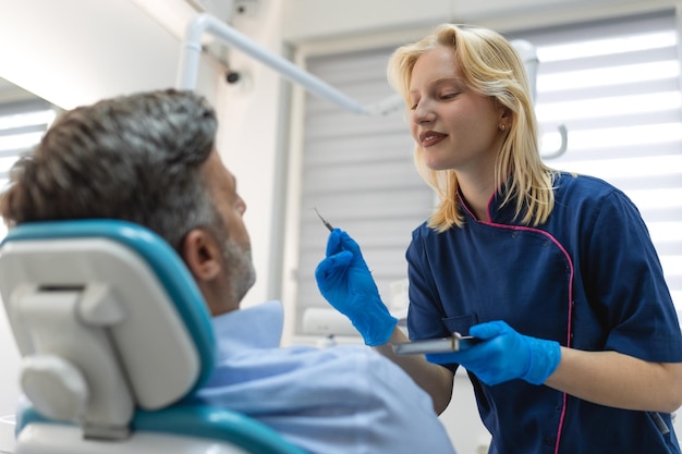 Une jeune femme dentiste et un patient scène de style de vie de bureau de dentiste cabinet médical soins de santé aux patients