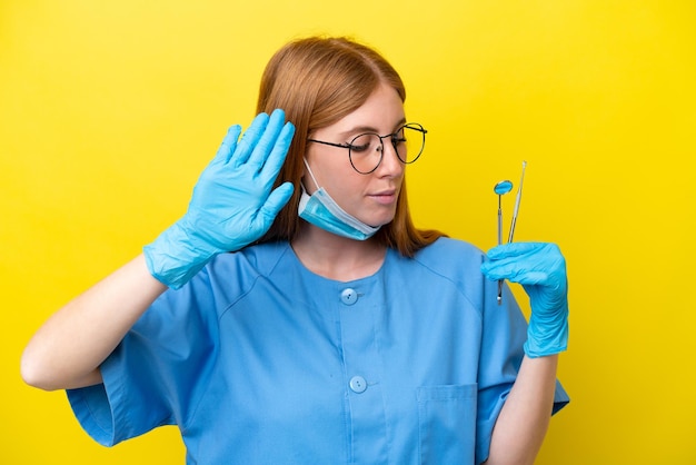 Jeune femme dentiste rousse isolée sur fond jaune faisant un geste d'arrêt et déçue