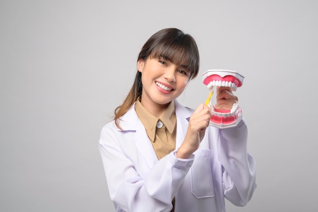 Jeune femme dentiste souriant sur fond blanc studio