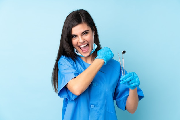 Jeune femme dentiste tenant des outils célébrant une victoire