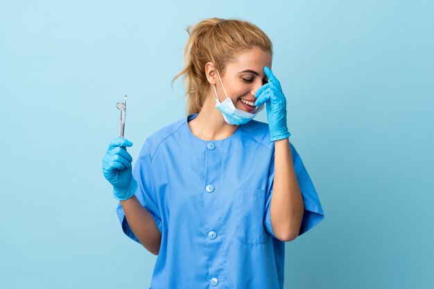 Jeune, femme, dentiste, tenue, outils, isolé, bleu, mur, rire