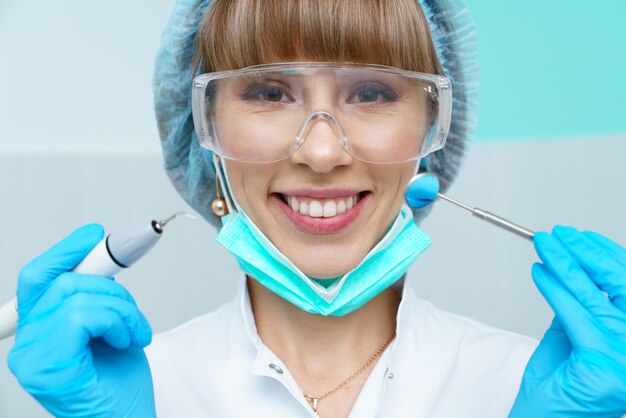 Jeune femme dentiste traitant les dents des patients en remplissant la cavité dentiste travaille avec des équip...