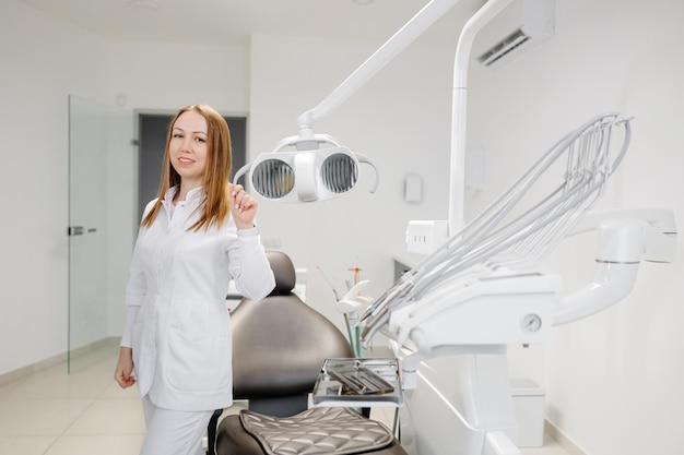 Une jeune femme dentiste en uniforme passe du temps dans le cabinet du dentiste