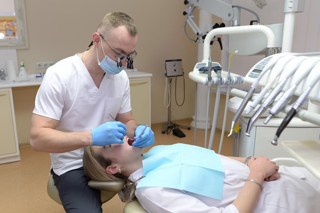 Une jeune femme dentiste vérifie les dents d'une fille lors d'un rendez-vous dans une clinique dentaire.