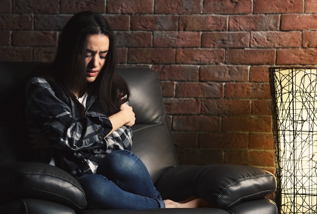 Jeune femme déprimée sur le mur de briques