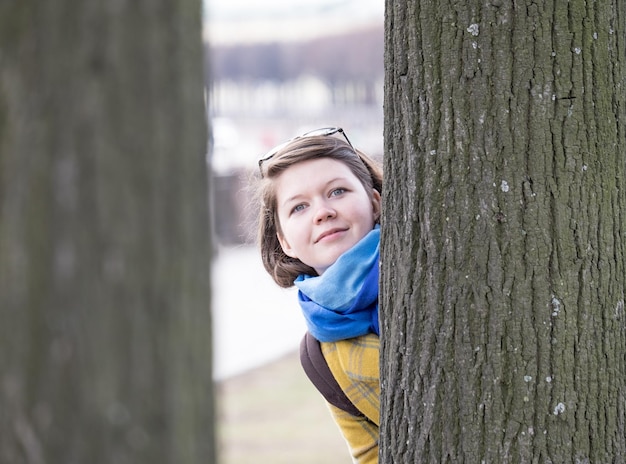 Une jeune femme derrière un arbre.