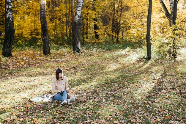 Jeune femme dessinant près d'un lac dans la forêt d'automne Croquis