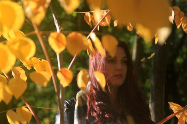 Une jeune femme détournant son regard alors qu'elle se tient près des feuilles d'automne