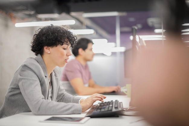 jeune femme développeur de logiciels utilisant un ordinateur de bureau tout en écrivant du code de programmation dans un bureau de démarrage créatif moderne