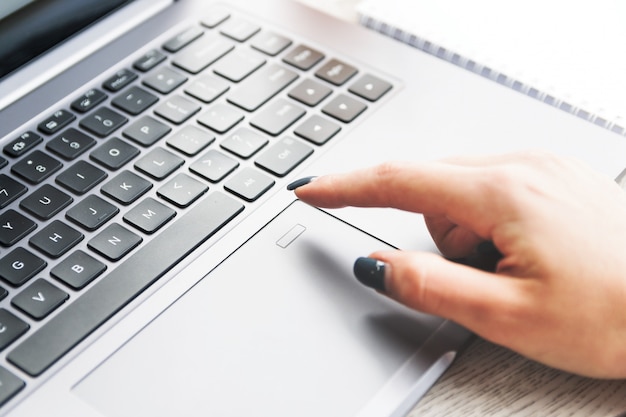 Jeune femme déverrouillant son ordinateur portable par scanner d'empreintes digitales.