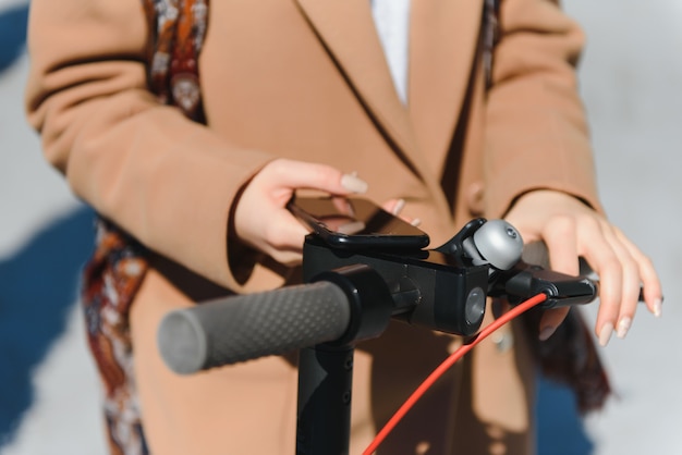 Une jeune femme déverrouille un e-scooter avec son téléphone portable