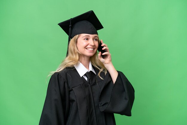 Jeune femme diplômée en anglais de l'université sur fond isolé en gardant une conversation avec le téléphone mobile