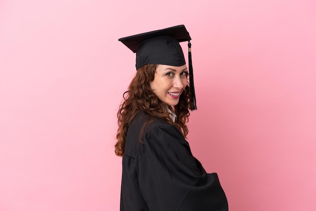 Jeune femme diplômée universitaire isolée sur fond rose avec les bras croisés et impatient