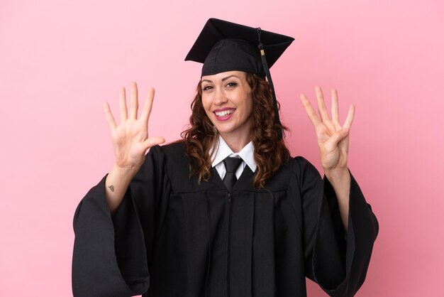 Jeune femme diplômée universitaire isolée sur fond rose comptant neuf avec les doigts