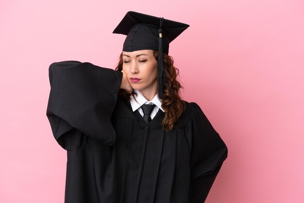 Jeune femme diplômée universitaire isolée sur fond rose avec des maux de cou