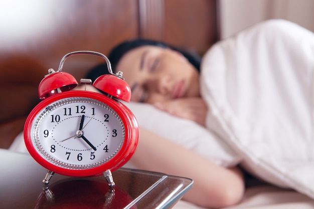 Jeune femme dormant dans son lit devant le réveil. l'heure de dormir