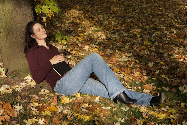 Jeune femme dormant sous un arbre en automne