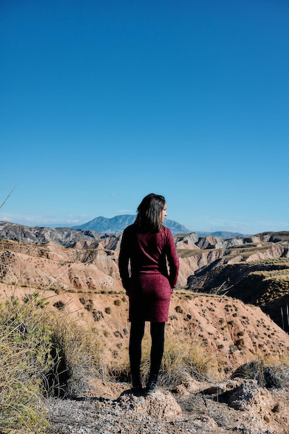 Une jeune femme le dos tourné devant l'entrée d'un désert en plein jour