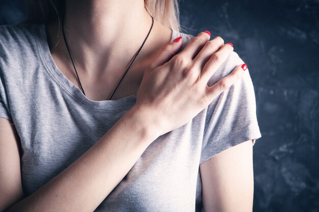 Photo la jeune femme a la douleur d'épaule sur le gris