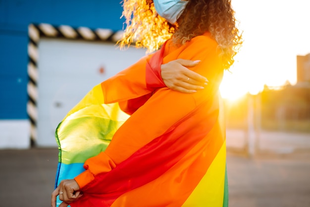 Jeune femme avec drapeau LGBT et masque de protection