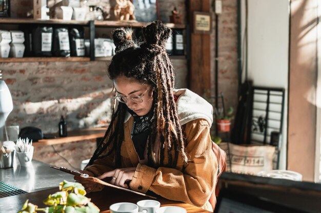 Jeune femme avec des dreadlocks à la cafétéria pointant son doigt vers le menu commandant sa nourriture