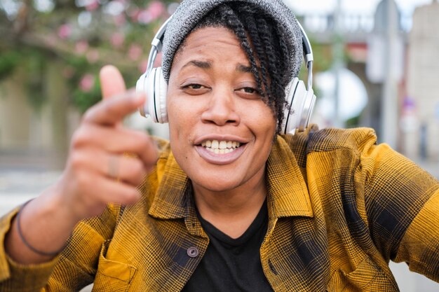 Jeune femme avec des dreadlocks couvertes d'un chapeau chantant à l'appareil photo à l'extérieur dans la ville de la musique rap de style urbain Concept Lifestyle