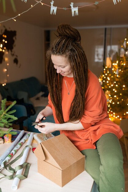 Photo jeune femme avec des dreadlocks emballant des cadeaux de noël