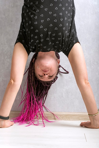 Jeune femme avec des dreadlocks roses se tient dans ses bras Fille fait le poirier Cadre vertical