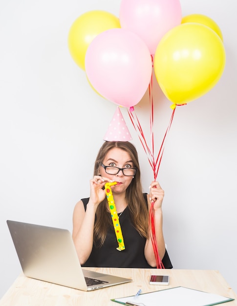 Photo jeune femme drôle célébrant le succès de son entreprise ou un anniversaire au bureau tenant des ballons de fête colorés.