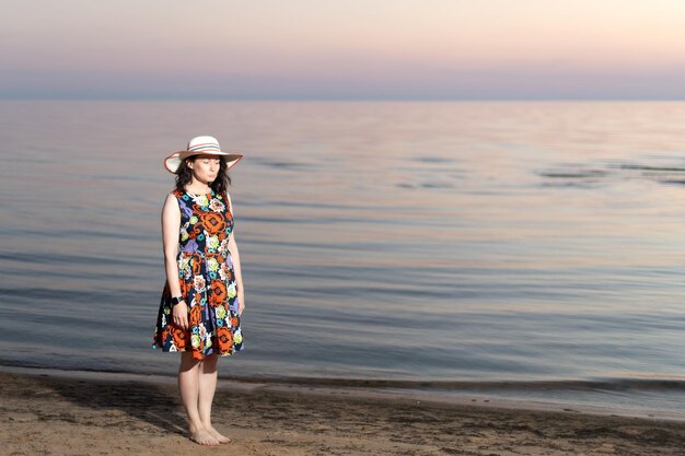 Une jeune femme avec une drôle d'expression de visage se tient sur le fond de la mer au coucher du soleil