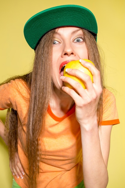 jeune femme drôle mange une pomme sur jaune
