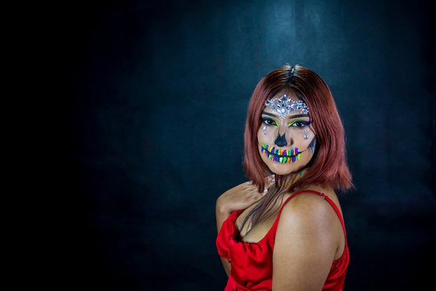 Jeune femme avec du maquillage pour halloween party costumé fond noir et chemisier rouge