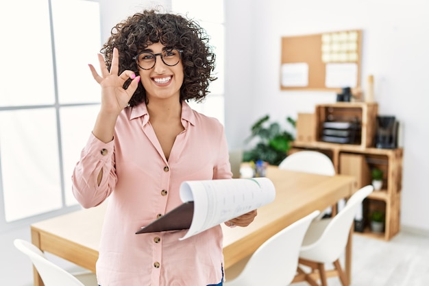 Jeune femme du Moyen-Orient portant un style d'affaires au bureau souriant positif faisant signe ok avec la main et les doigts. expression réussie.