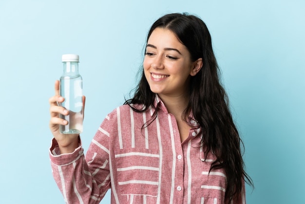 Jeune femme avec une eau isolée sur fond bleu avec une expression heureuse